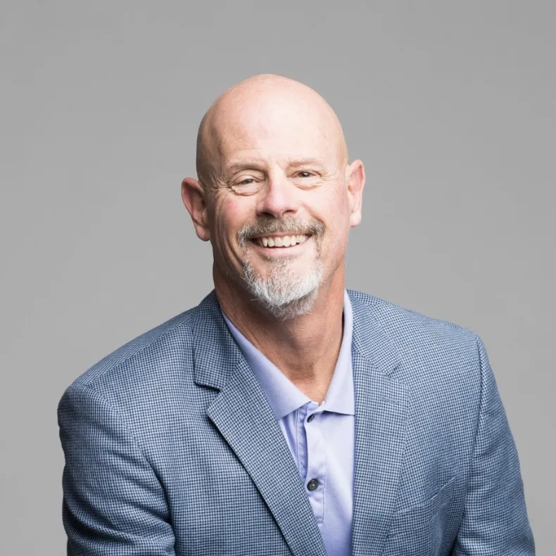 Portrait of attorney David Bateman, smiling, in a light blue blazer