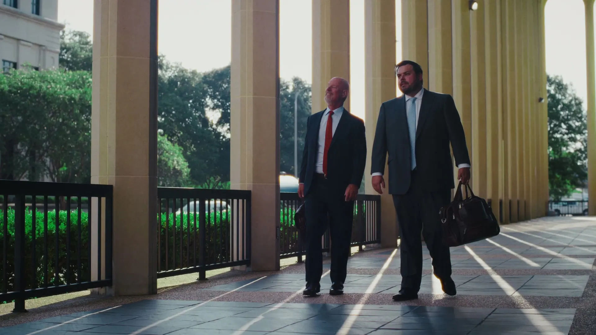 Attorneys David Bateman and Michael McDonald walking together under a stone colonnade in Baton Rouge